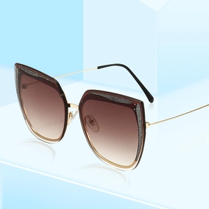 Occhiali da sole cat eye con montura glitter e stanghette in metallo dorato su blu