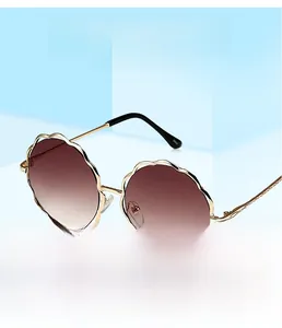 Détail de la monture dorée festonnée et verres dégradés marron de ces lunettes de soleil