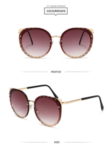 Detail view of cat eye sunglasses with gold wavy engraved frames and brown lenses