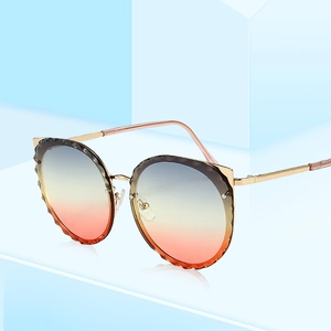 Cat ear gold frame sunglasses with gradient lenses and diamond-cut edges on blue block