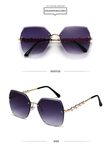 Detail view of gold metal sunglasses with purple gradient lenses and rhinestone wave design
