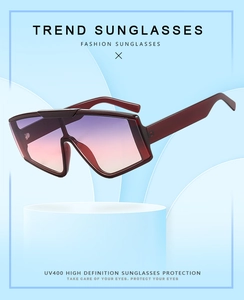 Detail of oversized square sunglasses featuring wine red frames and UV400 gradient lenses