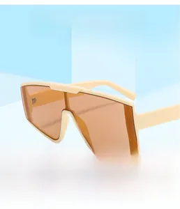 Detail of cream oversized shield sunglasses with orange lenses on a blue platform