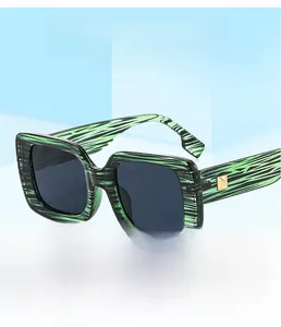 Detail of square sunglasses with green marble pattern frame and golden metal hinge detail