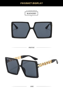 Detail of luxury square sunglasses with gold Greek key pattern on black metal temples