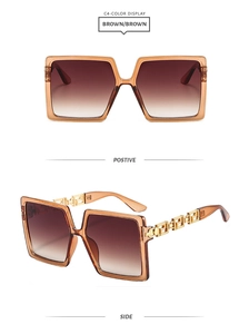 Macro detail of square amber frames with gold hollow Greek key temples on sunglasses