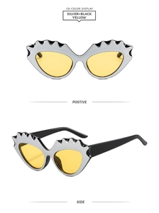 Close-up of wavy silver cat eye sunglasses with yellow lenses and black temples