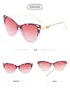 Detail view of cat eye sunglasses with purple gradient lenses and gold butterfly accents