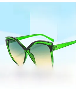 Détail de lunettes de soleil œil de chat vertes avec monture bicolore et clous dorés