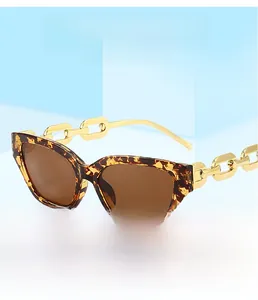 Detail of tortoise frame sunglasses featuring bold golden chain temples and brown lenses