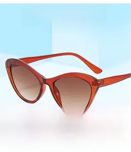 Cat eye sunglasses with amber red frames and gradient lenses on a blue background