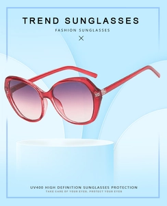 Detail of red translucent sunglasses with purple gradient lenses on a blue display stand
