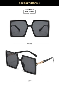 Close-up of black oversized square sunglasses with stylish gold chain temple accents