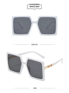 Detail view of large square white sunglasses with grey lenses and gold chain temples