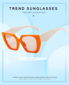 Close-up of orange geometric cat-eye sunglasses with white temples and UV400 protection