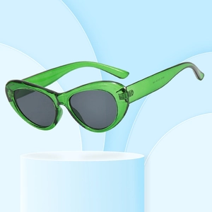 Lunettes de soleil œil de chat à monture verte translucide sur fond créatif bleu