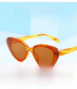 Detail of trendy semi-rimless cat eye sunglasses in translucent orange with dark lenses