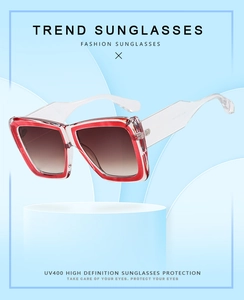 Detail of square oversized sunglasses with white and red frames and gradient brown lenses
