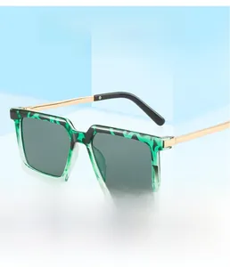Detail einer quadratischen Sonnenbrille mit grüner Schildpatt-Fassung und Goldbügeln