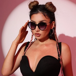 Occhiali da sole cat eye neri con lenti sfumate viola indossati da una modella