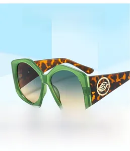 Détail de lunettes de soleil vertes oversize avec feuille dorée et branches écaillées