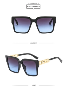 Detail of square black sunglasses with thick frames and thick gold chain link temples