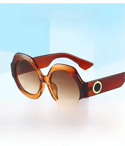 Détail de lunettes de soleil en ambre écaillé avec verres dégradés bruns et décorations dorées