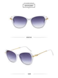 Close-up of white cat-eye sunglasses with gold hollow temples and gradient lenses