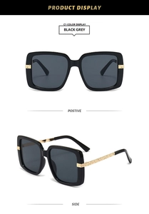 Detail of square black sunglasses with textured gold metal temples and grey lenses