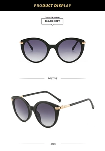 Dettaglio degli occhiali da sole cat-eye neri con accenti dorati e lenti grigie sfumate
