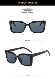 Détail de lunettes de soleil carrées noires avec branches larges et verres gris foncé