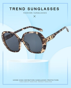 Detail of tortoise shell sunglasses featuring golden logo and UV400 protective lenses