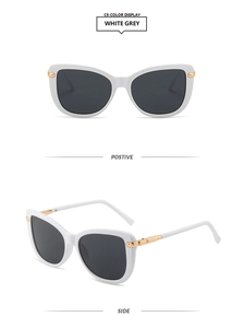 Detail of white cat-eye sunglasses with grey lenses and gold metal hinge accents