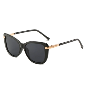Classic black oversized cat-eye sunglasses with gold metal hinges on a white background