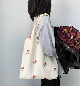 Close-up of red cherry embroidery on cream canvas tote bag with large capacity