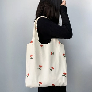 Detailed embroidery of red cherries with green leaves on a white mesh canvas tote bag