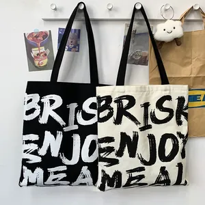 Detail of canvas tote bags with BRISK ENJOY MEAL letter print in black and white