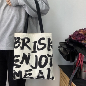 Detail of white canvas tote bag with black Brisk lettering and stylish shoulder strap