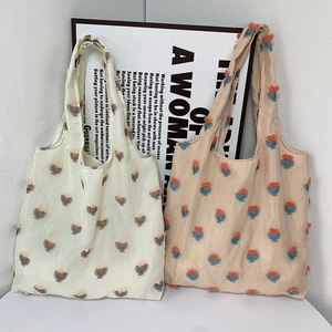 Detail of canvas tote bags with 3D embroidered floral patterns in beige and pink