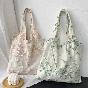 Detail of floral mesh tote bags with orange daisy and green botanical embroidery