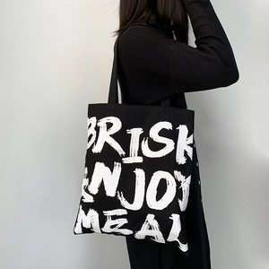 Close-up of black canvas tote bag featuring large white minimalist letter print