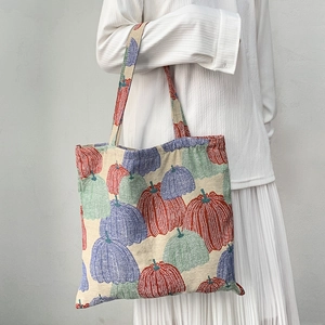 Artistic pumpkin embroidery tote bag with long shoulder strap shown on a model