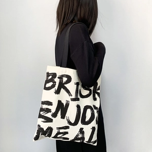Detail of white canvas tote bag with black letter print and durable shoulder straps