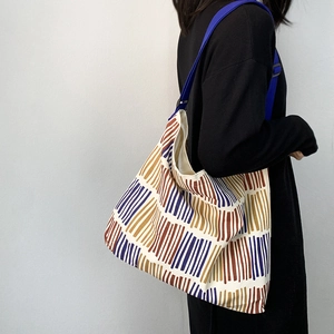 Detail view of large canvas crossbody bag with colorful geometric stripes and adjustable strap