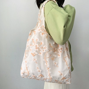 Detailed close-up of daisy floral embroidery on translucent mesh tote bag for women