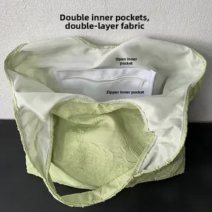 Detail view of the dual inner lining and zipper pocket inside a leaf-textured tote bag