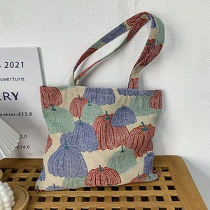Detail of colorful pumpkin jacquard fabric and woven handles on a canvas tote bag