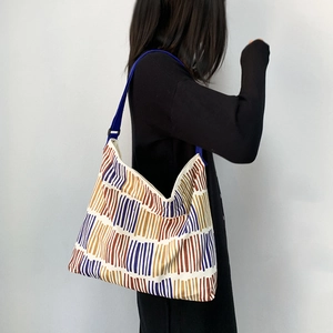 Detail of colorful striped canvas tote bag with adjustable blue strap and large capacity
