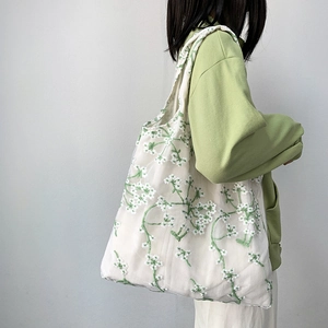 Detailed close-up of floral embroidery on white translucent mesh canvas tote bag