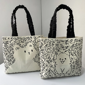 Detail of canvas tote bag with cartoon dog print and black ruched satin handles